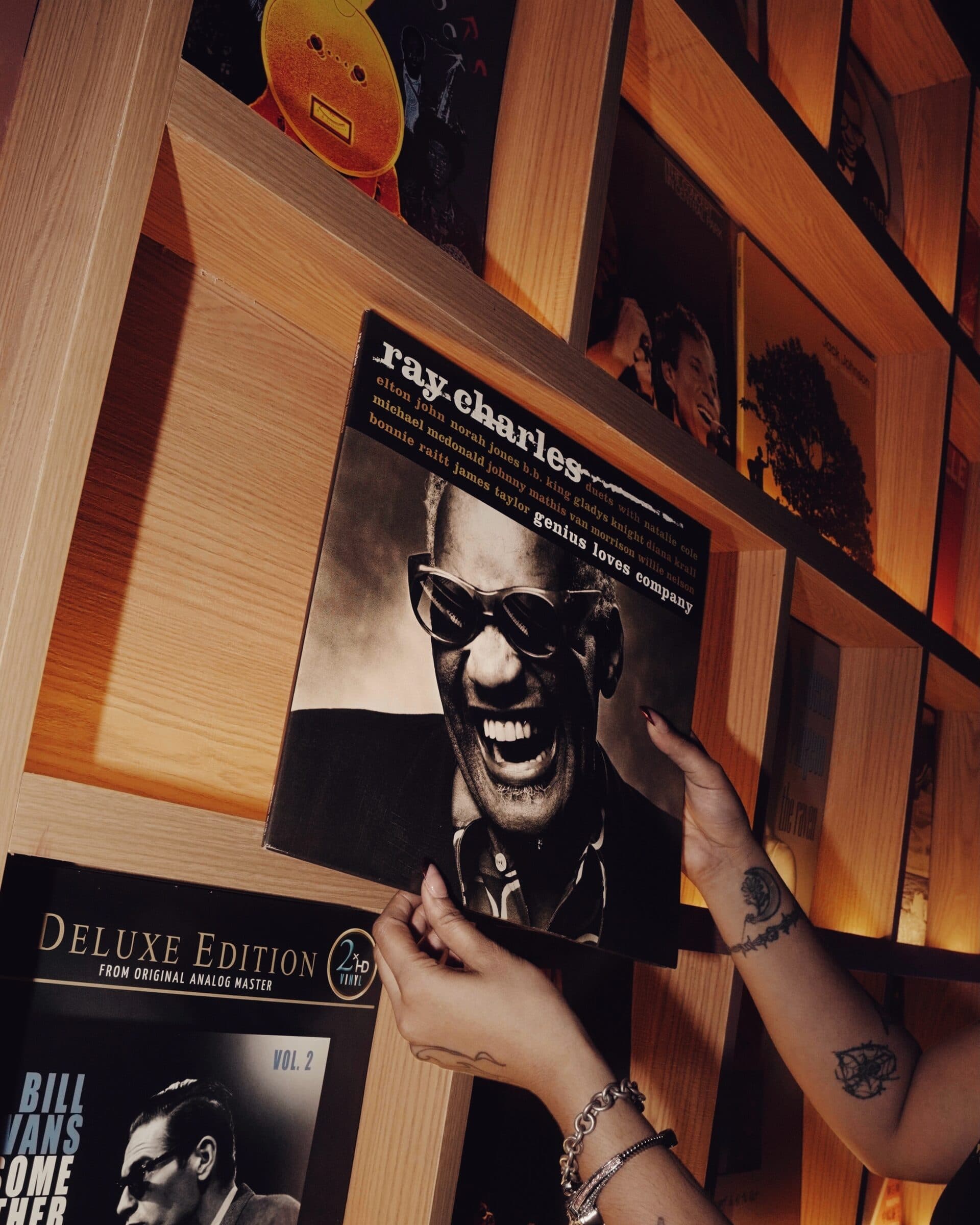 A hand holding a Ray Charles record against the shelves