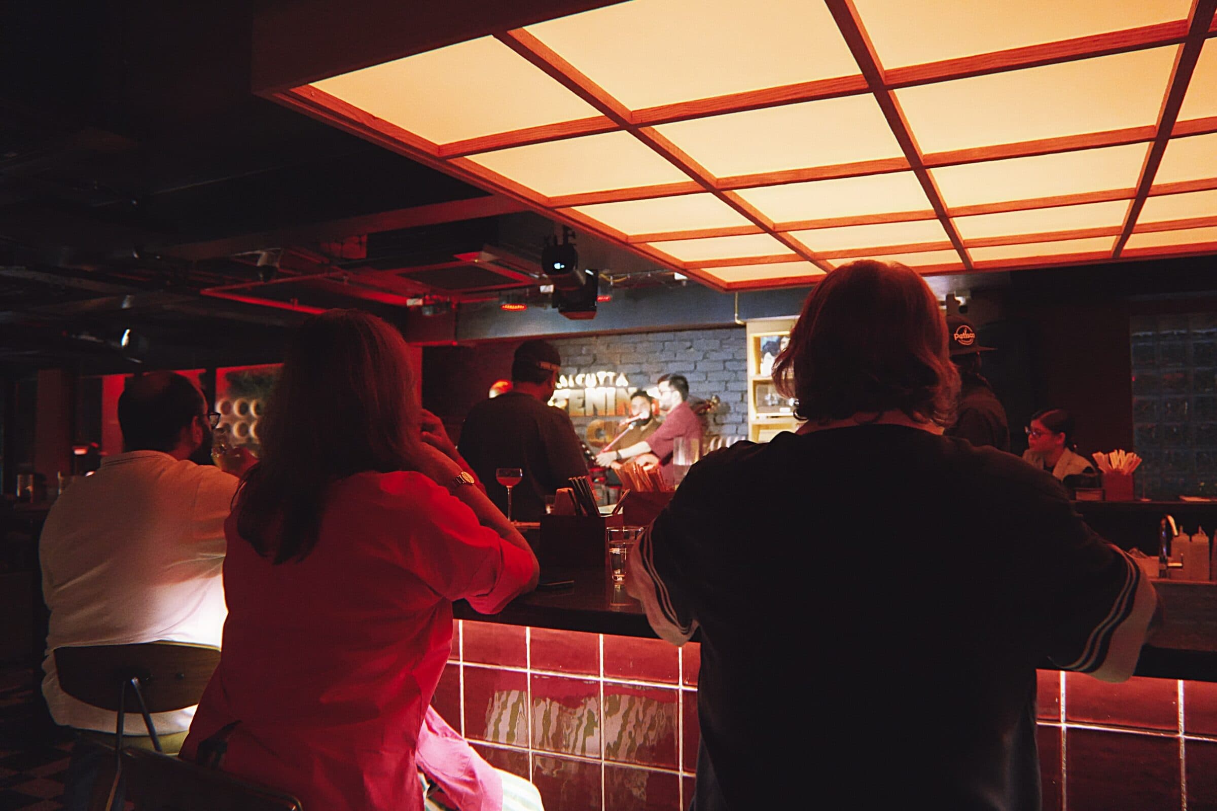 Guests at the bar under the glowing orange ceiling of the listening room